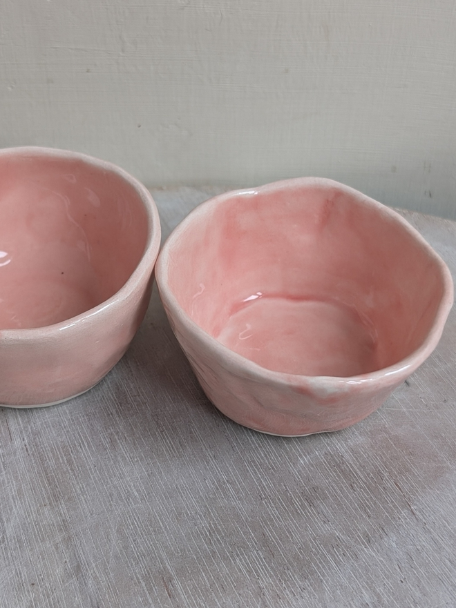 salt and pepper pink ceramic pinch pots from above on a wooden surface