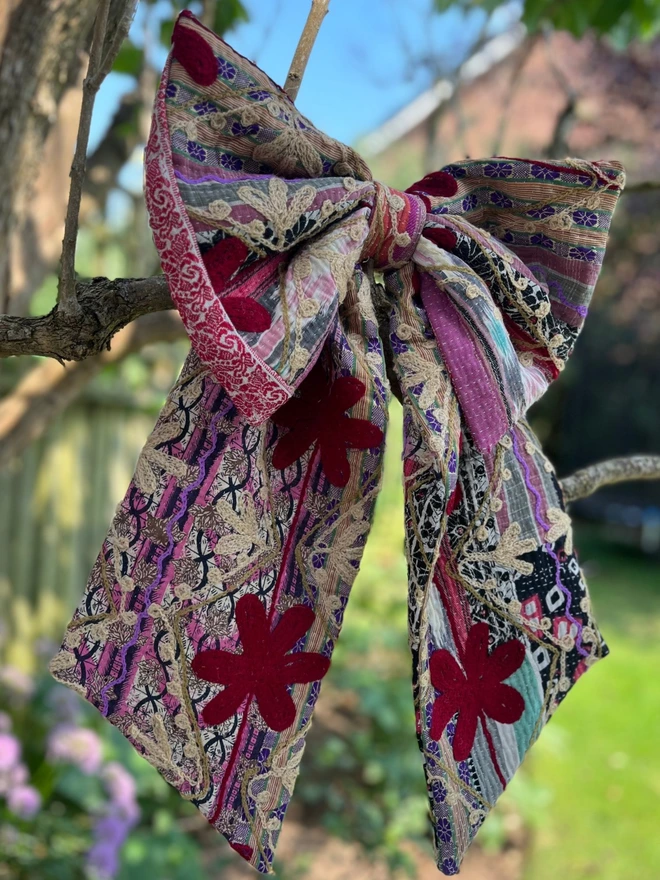 Large decorative bow, handmade from vintage kantha fabric in reds and pinks with additional embroidery flowers 