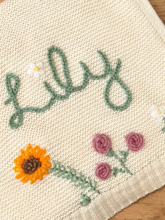 Hand Embroidered Baby Blankets, a hand embroidered blanket sitting on a wooden surface. 
