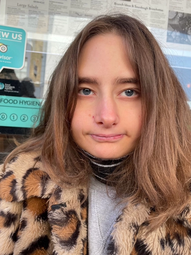 Piper autistic deaf teenage artist from hackney looking straight at the camera in her leopard print coat