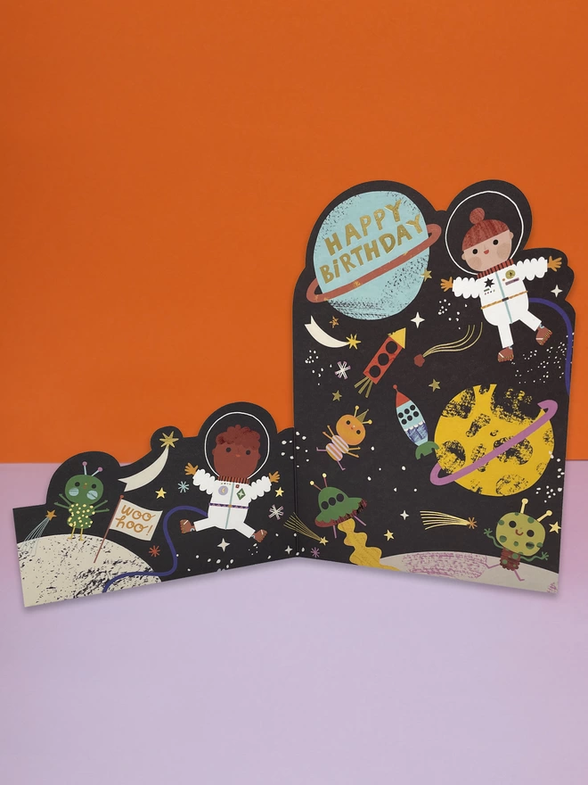 A space adventure themed, children’s birthday card, with colourful space rockets, planets and aliens, and astronauts. The card is complete with gold foil details and a gold foil ‘Happy Birthday’ message