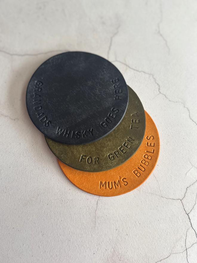 hand stamped leather coasters, in navy, olive and yellow