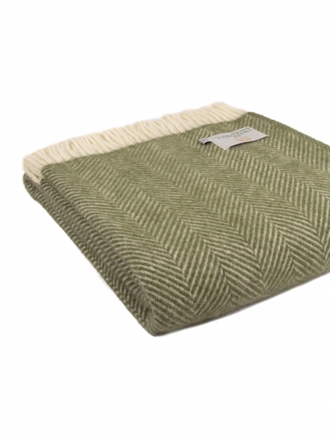 Lambswool olive throw folded on a white background.
