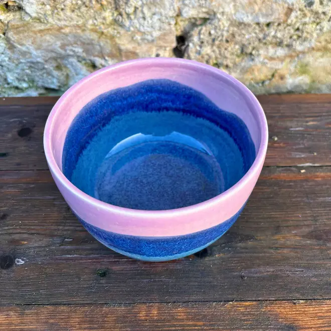 Landscape Small Bowl, a colourful bowl sitting on a wooden surface against a brick backdrop. 