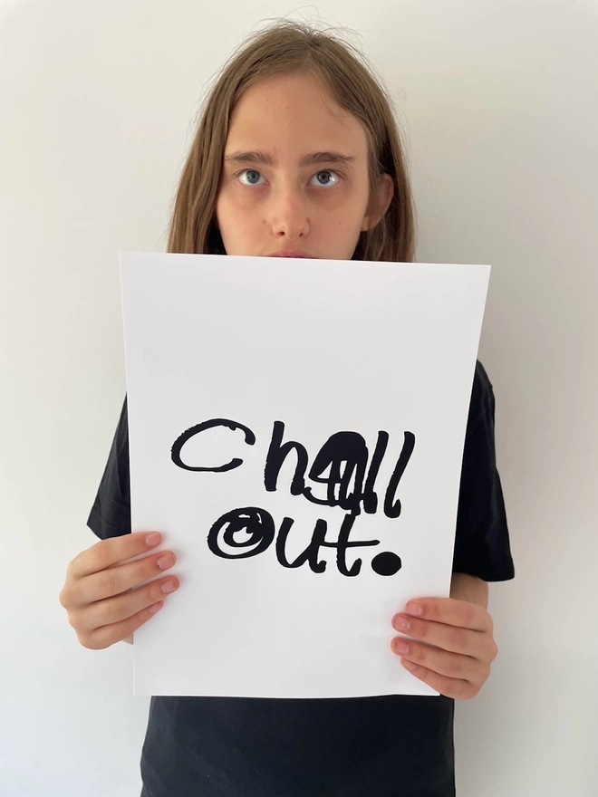 Piper is holding up her digital print that she has written in bold black pen on a white background