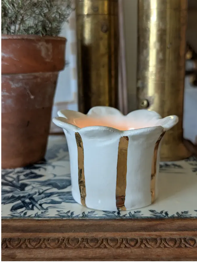 Gold Daisy tealight holder,  ceramic. In a kitchen setting.