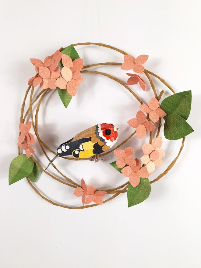 goldfinch sculpture, perched on a wreath of peach hydrangea blooms