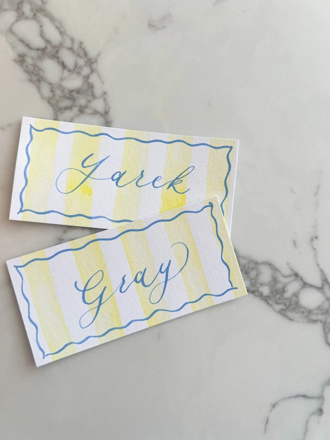 Personalised calligraphy event place cards, yellow striped coloured place cards with blue calligraphy name
