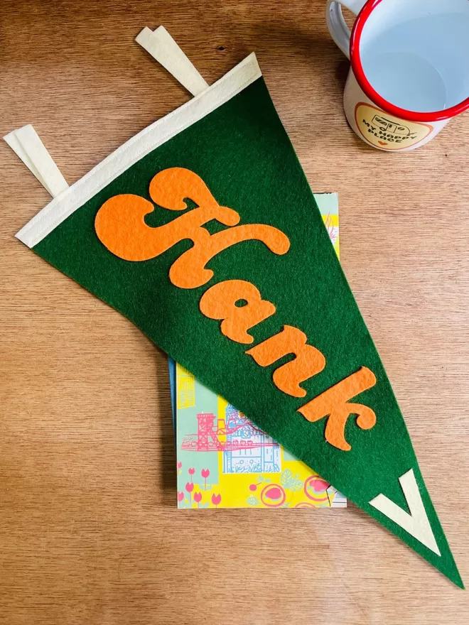 Green and orange campervan sign laying on a wooden table with a camping mug