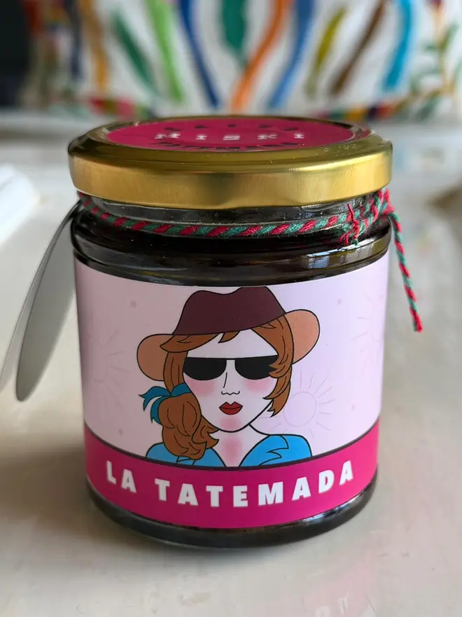 'La Tatemada' Salsa Jar (Set Of 1-4 Jars), a jar of salsa sitting on a kitchen counter top. It has the icon of a woman. 