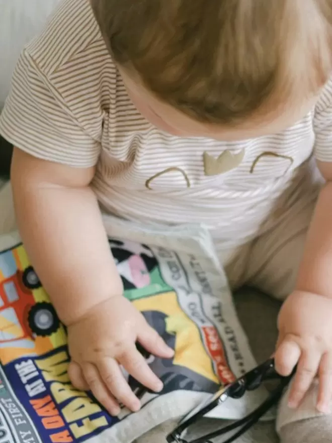 Baby reading farm newspaper with specs