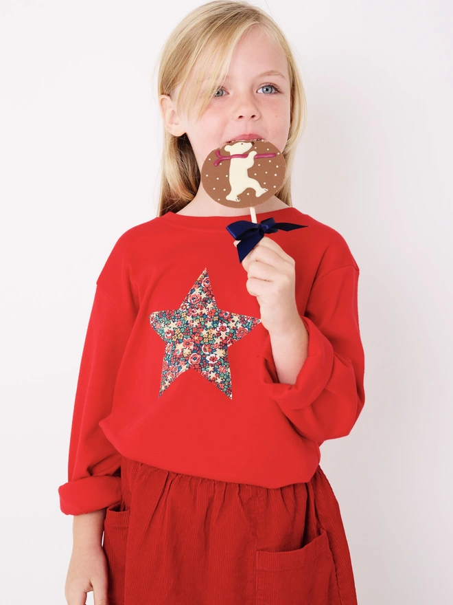 a 5 year old girl wearing a red t-shirt with a floral Liberty star shape on the front.