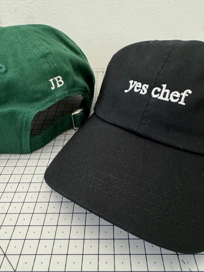 Yes Chef Cap in Classic Cotton Black, and Bottle Green. The Green cap shows the cap from behind with the back embroidered initials.