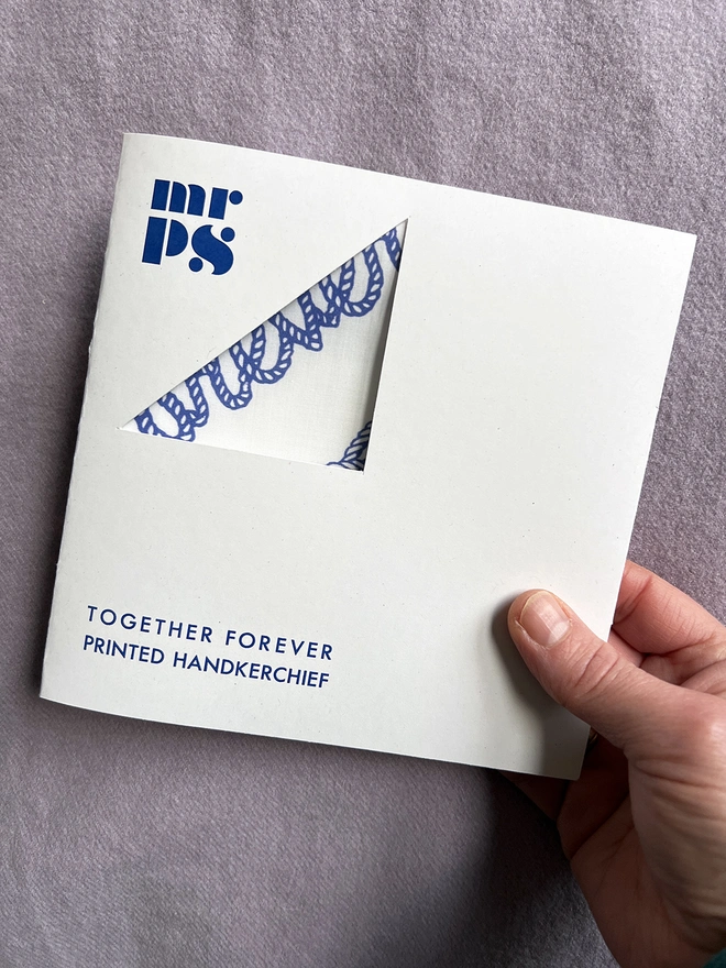 A hand holds the wallet packaging the Mr.PS Together Forever Handkerchief