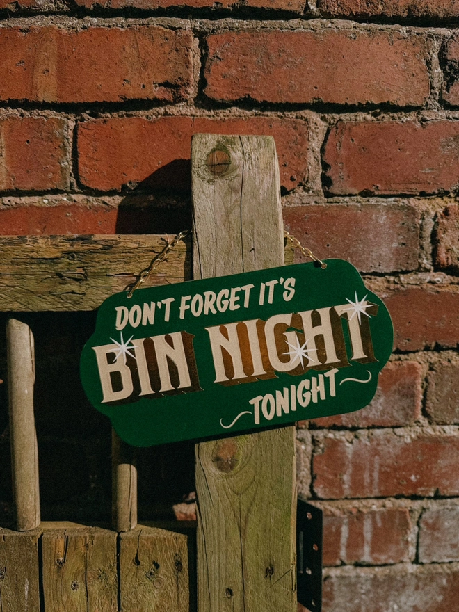 green 'dont forget it's bin night tonight' sign with gold text and hanging chain