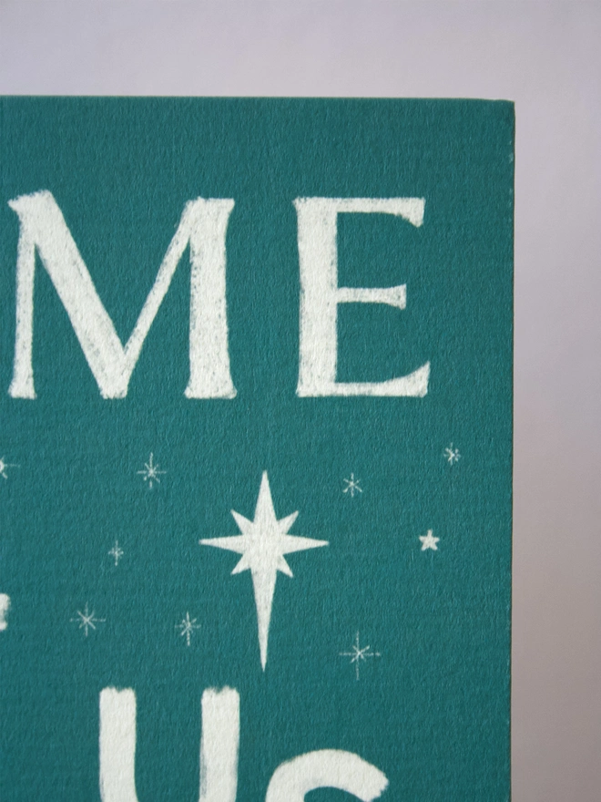 Green Christmas card with the words 'come let us adore him' on the front