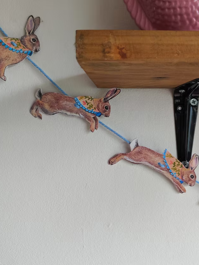illustrated easter bunny garland. bunnies with easter scarves on bunting hung on a wall.