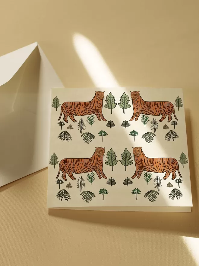 Annika Reed Studio woodblock print of four tigers among trees seen on a card.