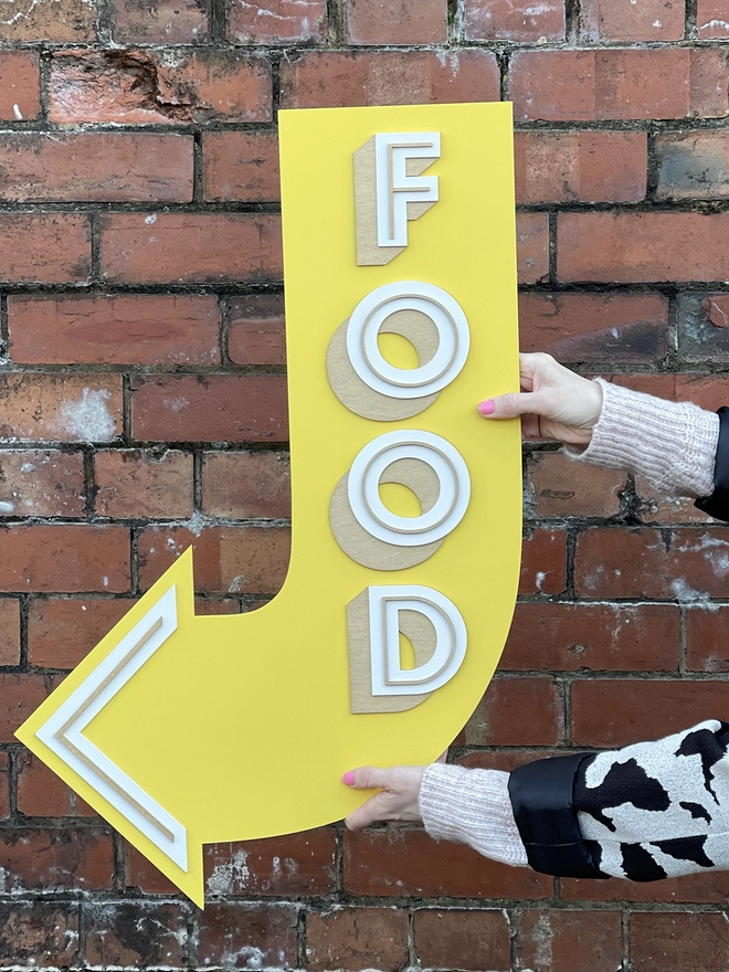 a yellow wooden arrow pointing to the left which reads FOOD