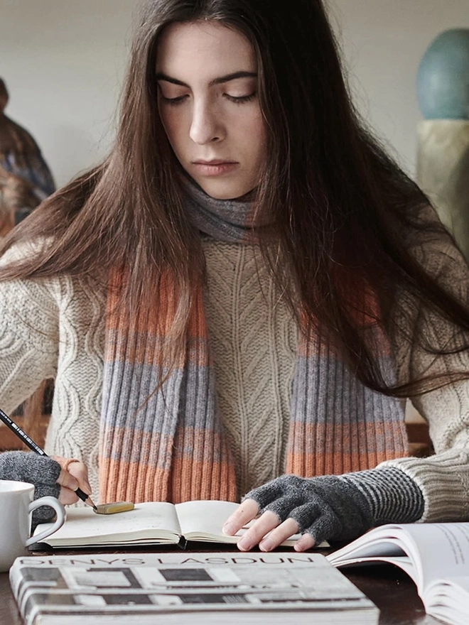 Lambswool Striped Scarf, a woman wearing a colourful striped scarf indoors. 