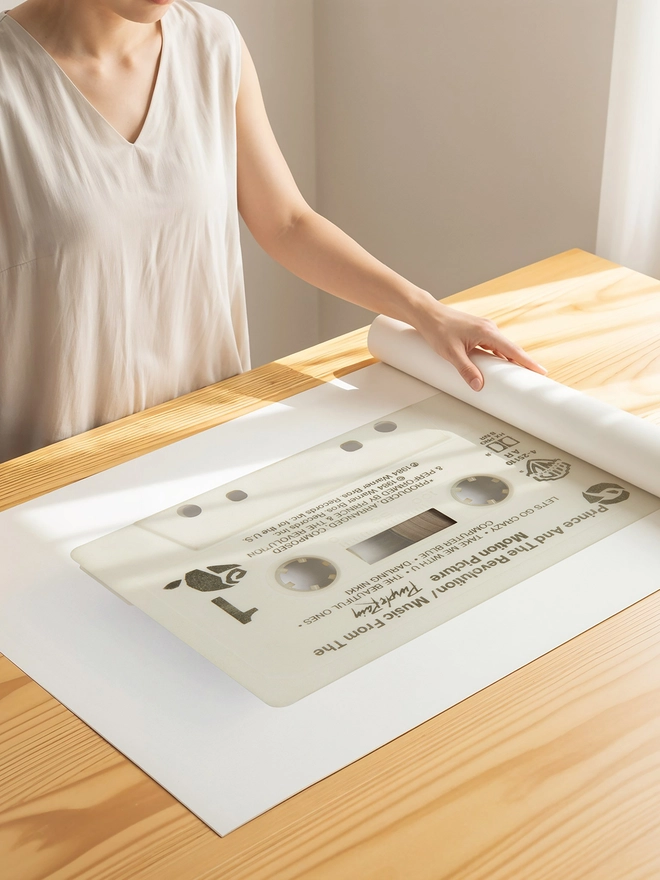 prince purple rain cassette tape print. print being unrolled on wooden table.