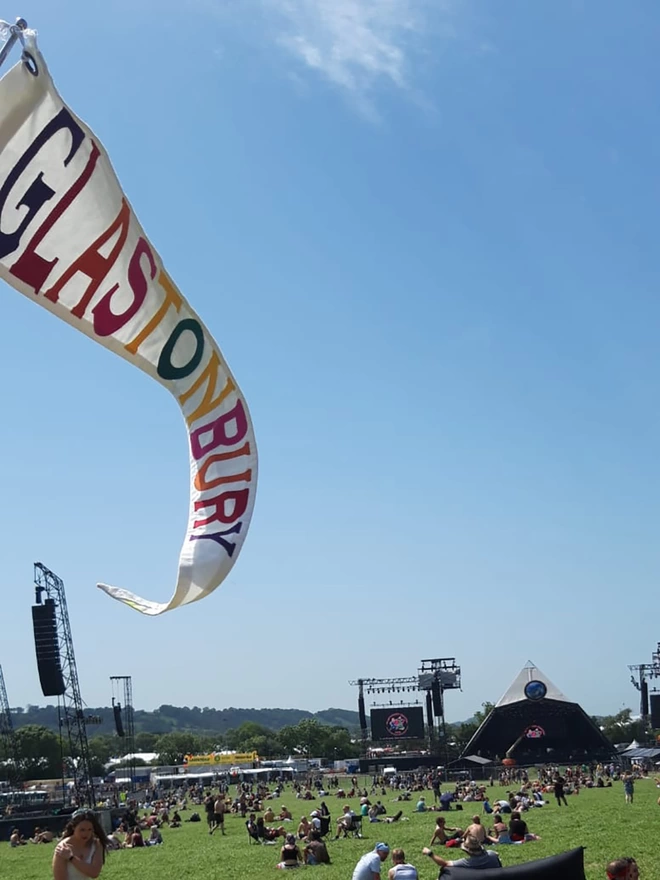 An ivory canvas pennant flag with multi coloured letters at the Glastonbury festival