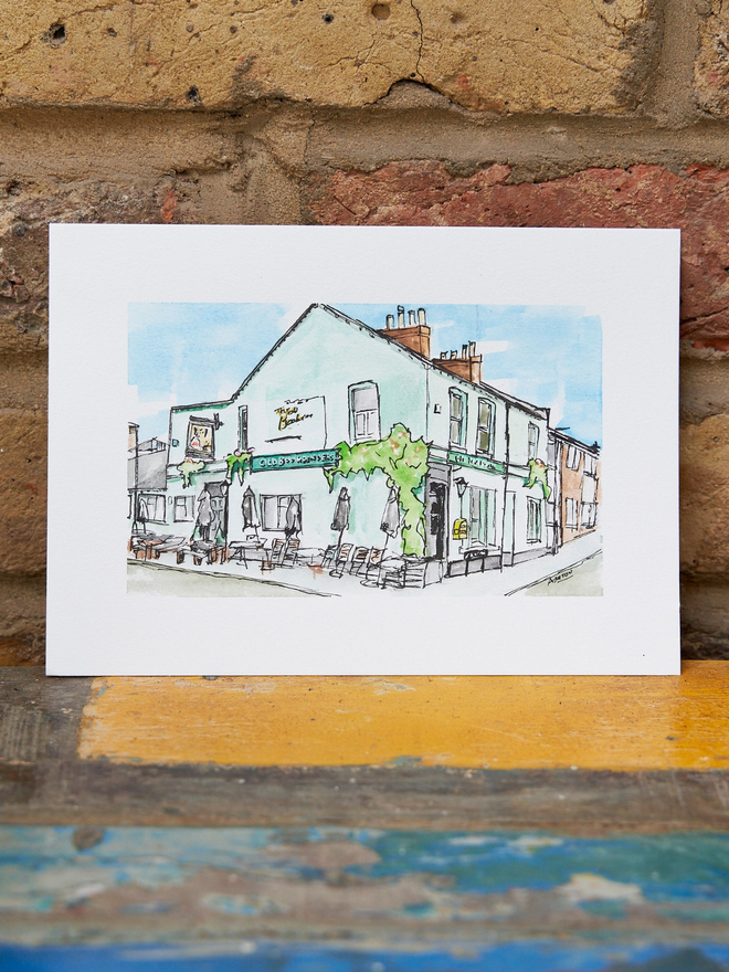 A5 watercolour pub painting leaning against a brick wall