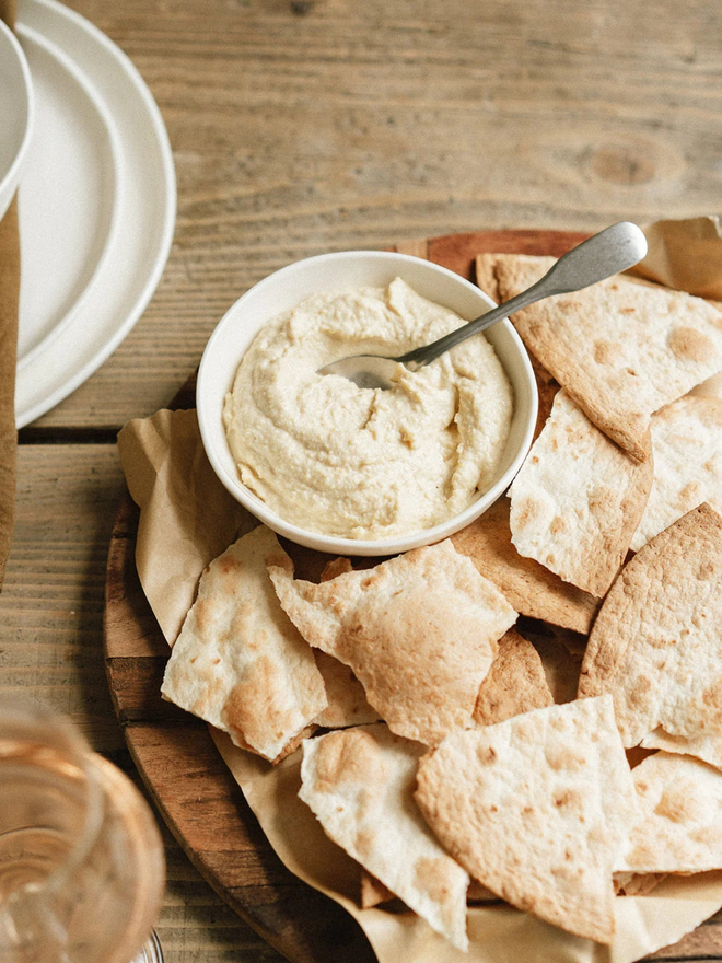 'milk' handcrafted stoneware bowl. a white serving bowl holding hummus with pita bread.