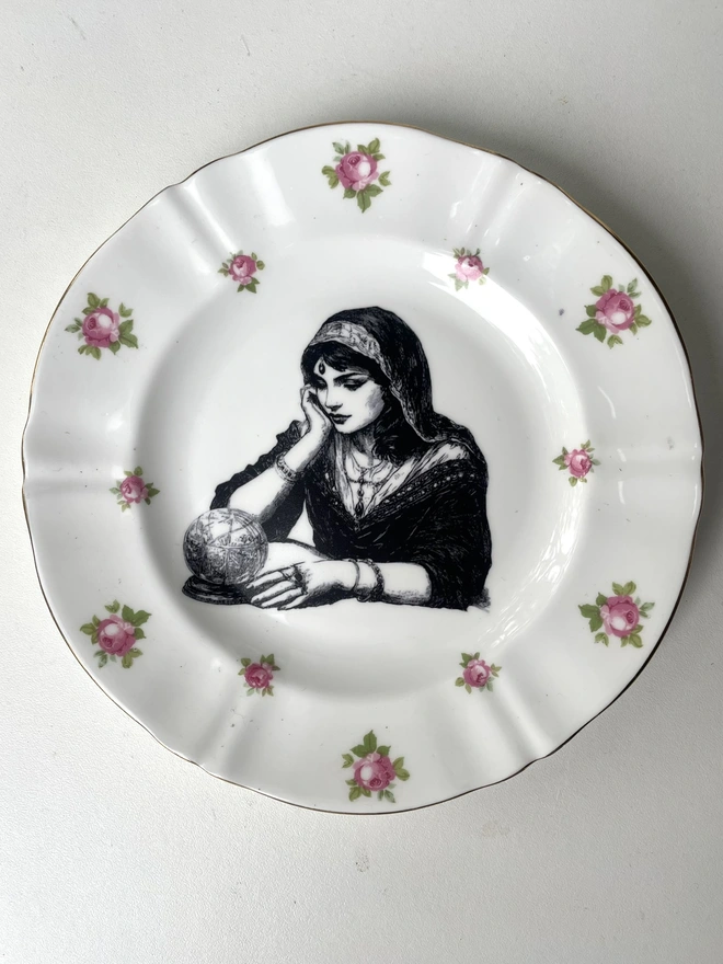 a vintage ornate plate with a pink floral detail, in the centre i have printed a vintage black and white illustration of a pretty fortune teller reading a crystal ball