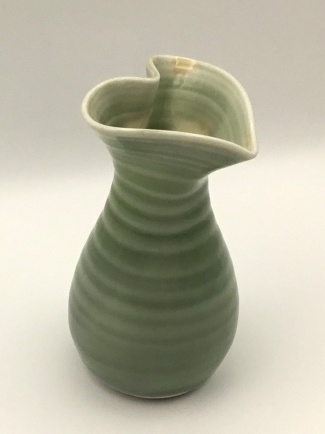 porcelain green heart shaped vase. a green vase with a heart shape opening and round base.