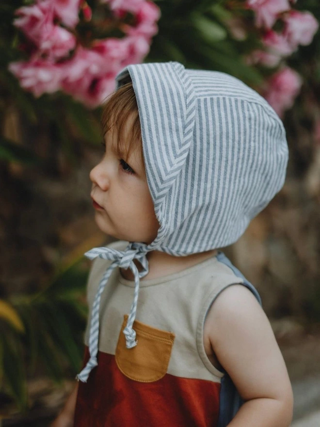 side view of little boy in his stripe brim sun hat