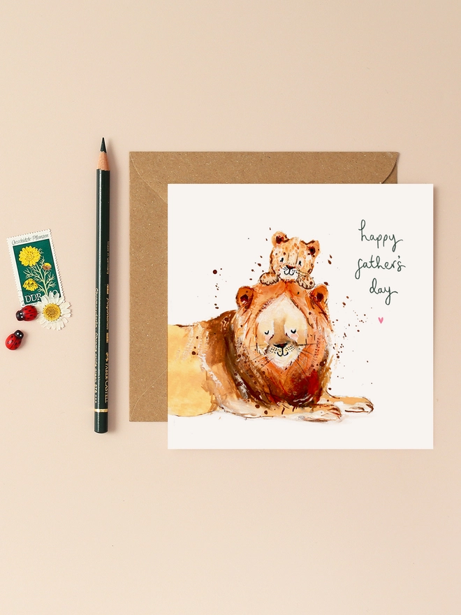 A heartwarming illustration featuring a proud lion and its playful cub, both sporting joyful expressions. The lion's mane is depicted with soft, flowing lines, while the cub gazes up with wide, innocent eyes. Above them, the handwritten message "Happy Father's Day" adds a personal touch. The design combines earthy tones and gentle textures, capturing the warmth and affection of the duo.