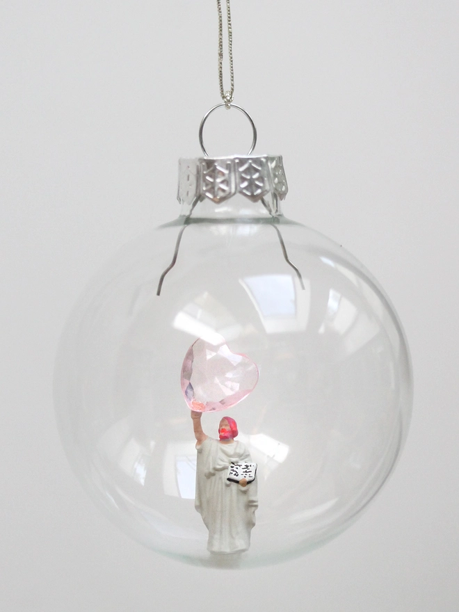 miniature jesus figure holding a heart in a glass christmas bauble