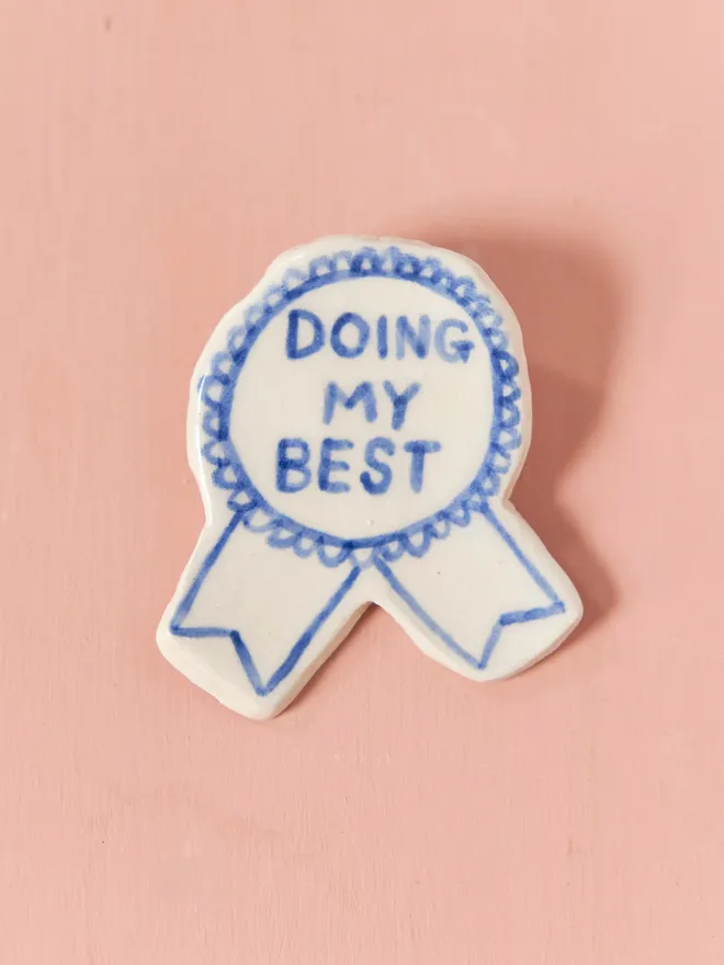  Blue Handmade Ceramic Award, a blue and white ceramic award badge sitting on a pink surface