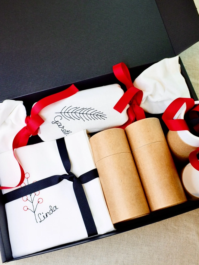 Christmas cracker fabric gift box with embroidered napkins and black and red ribbon bows