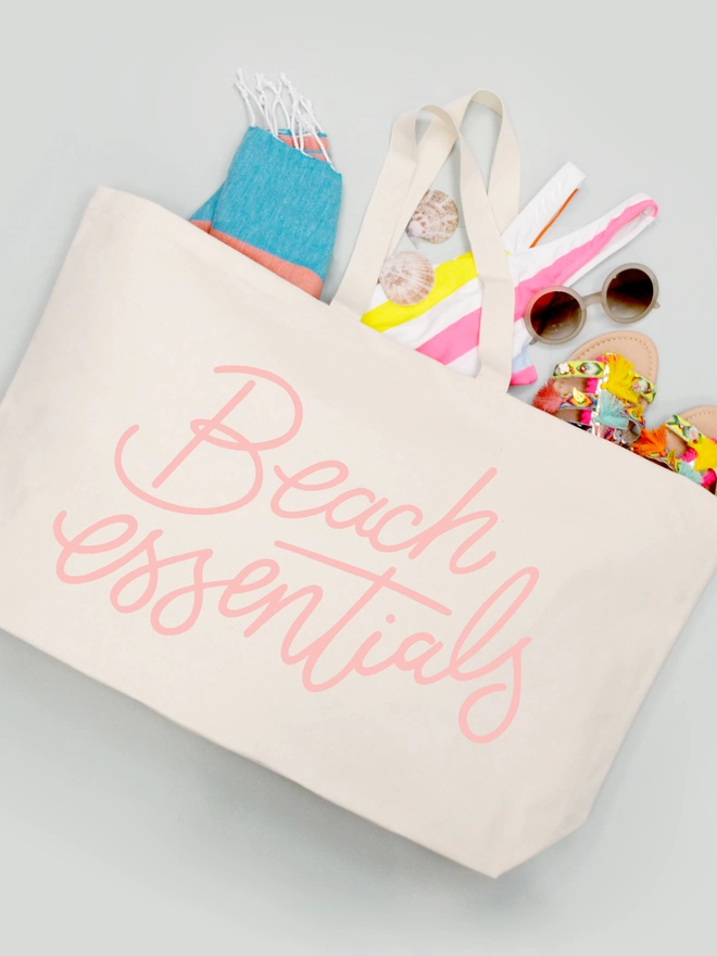 oversized natural canvas tote bag with beach essentials slogan with beach items spilling out