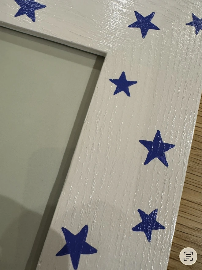 Close up of blue stars on child’s wooden hand painted photo frame 