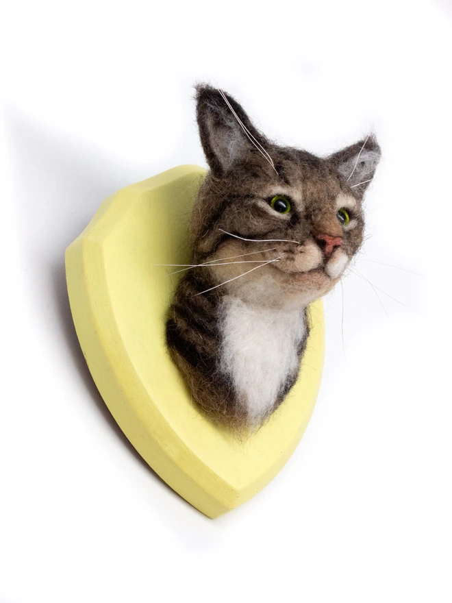 A handmade needle-felted custom tabby cat petportrait mounted on a yellow wooden shield 