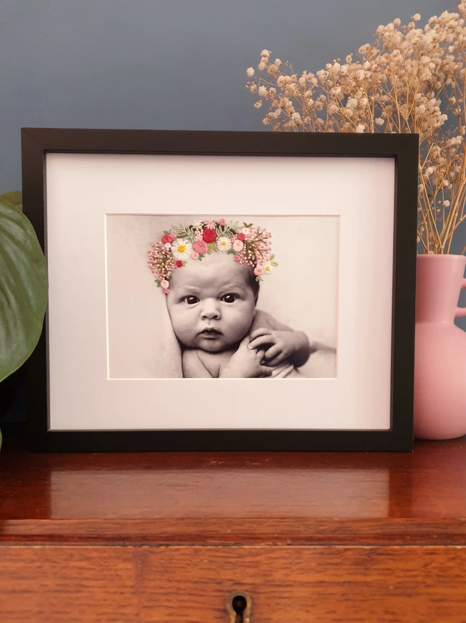 Baby photo with hand embroidered pinks and white flower crown, in black frame