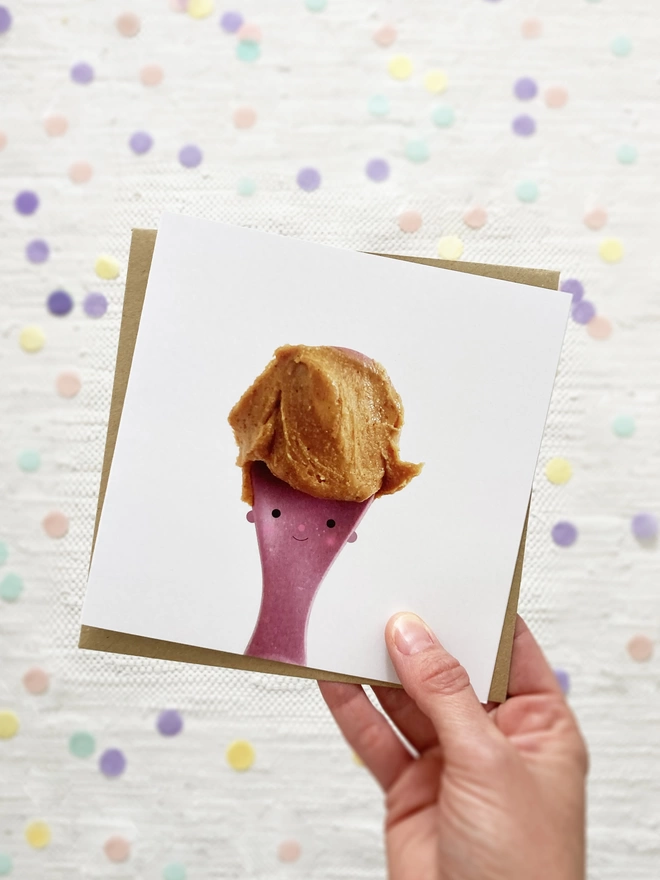 A lady holding a card. A purple spoon with peanut butter hair 