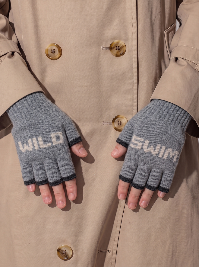 Lifestyle image of the Grey and Cloud Wild Swim Mittens worn against a beige button down coat
