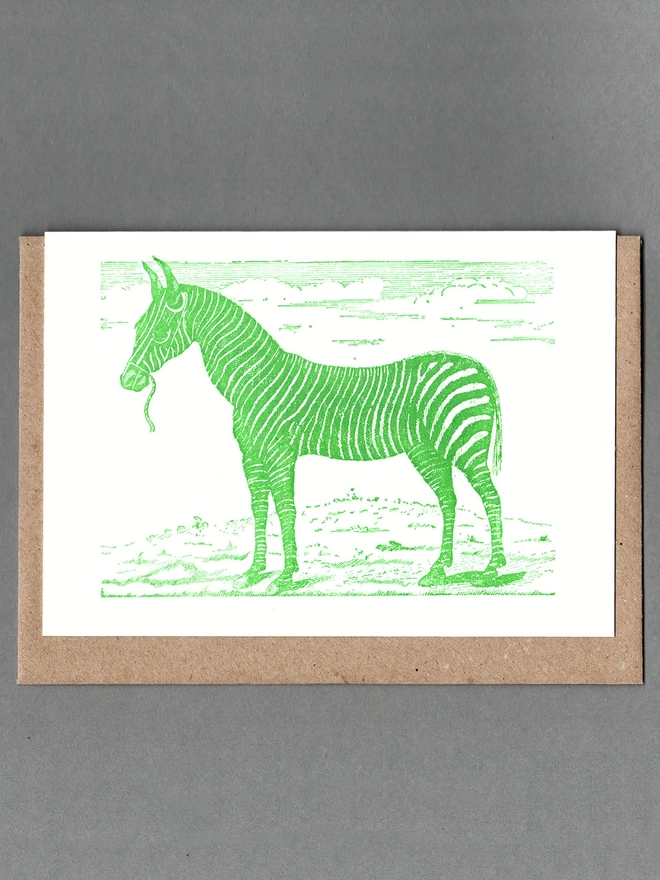 White card with green illustration of a zebra with a brown envelope behind