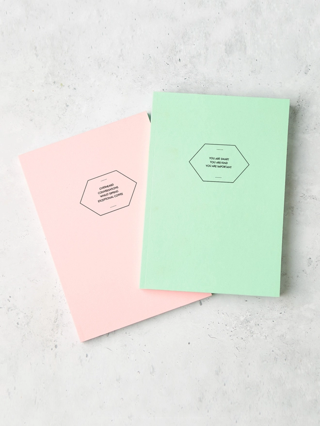 two colourful notebooks with minimalist personalised text on the cover 
