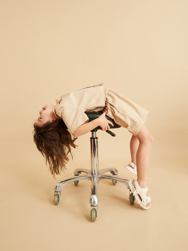 cool stylish girl in matching beige set like a wedding outfit lying backwards over a chair