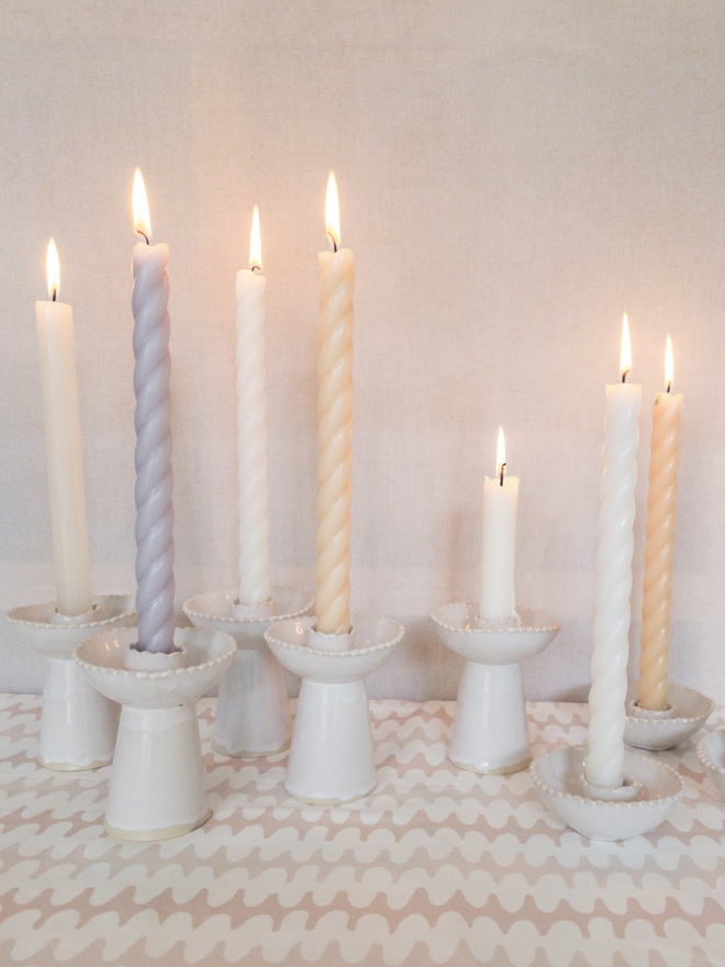 a group of white tall candlestick holders with lit candles