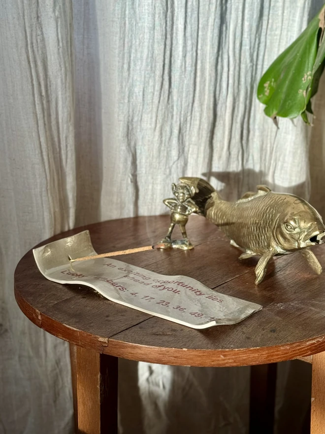 Fortune Incense Holder, an incense holder sitting on a wooden surface. It is joined by a fish sculpture. 