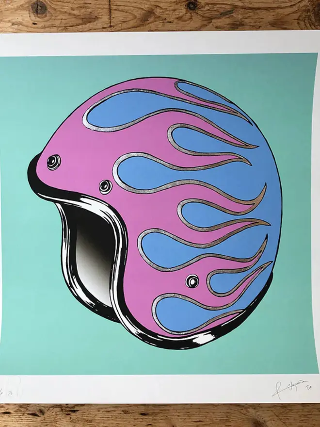 Motor cycle helmet with  a flame design on a teal background.
