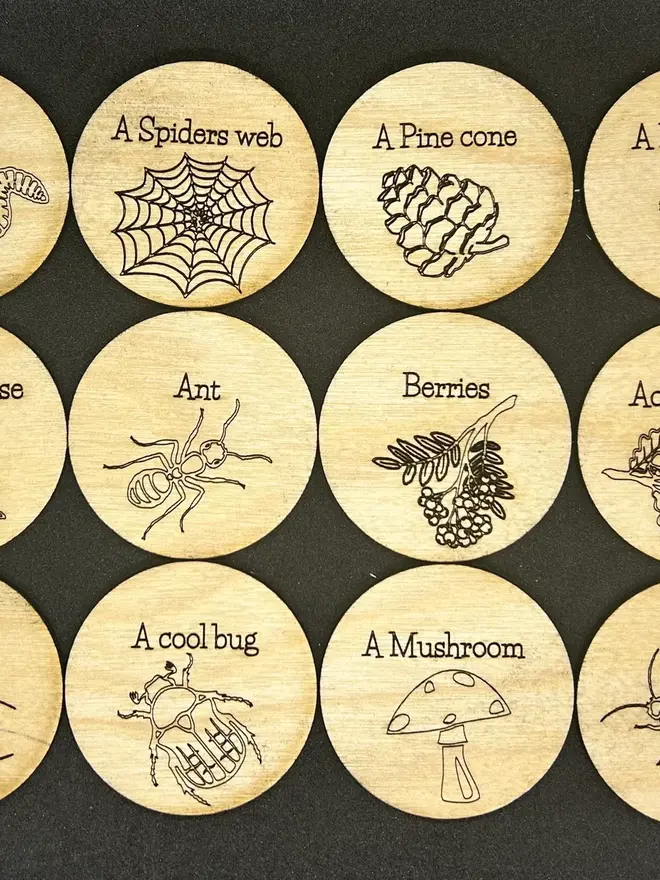 Wooden Nature Trail scavenger and mindfulness discs engraved with prompts and nature illustrations displayed on a table. 