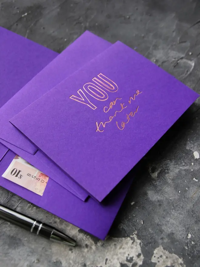 Hand foiled cash card or money wallet in a royal purple colour handfoiled in shiny rose gold foil text which says ‘you can thank me later’.