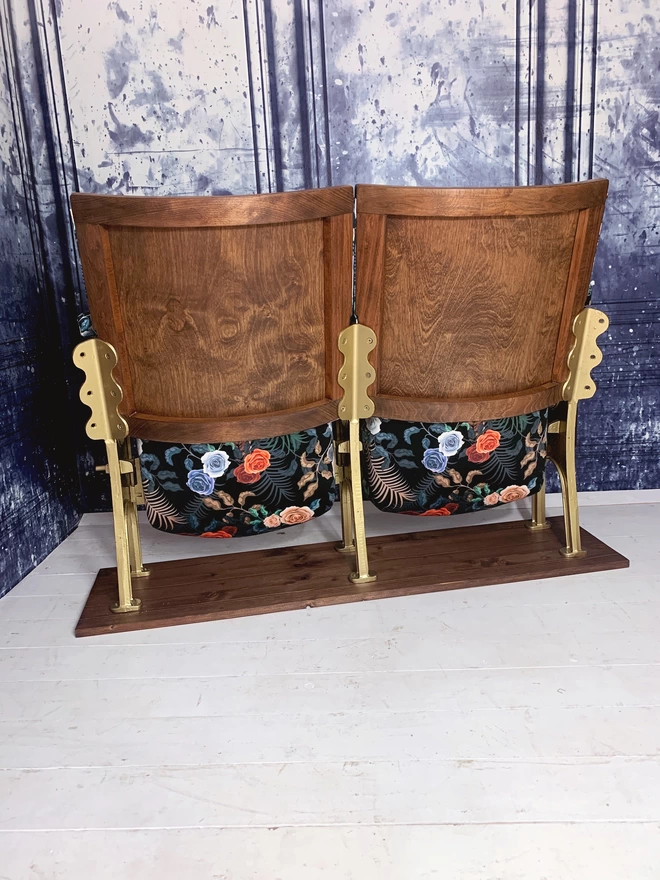 Rear view of a set of two vintage cinema seats against a blue marbled wall